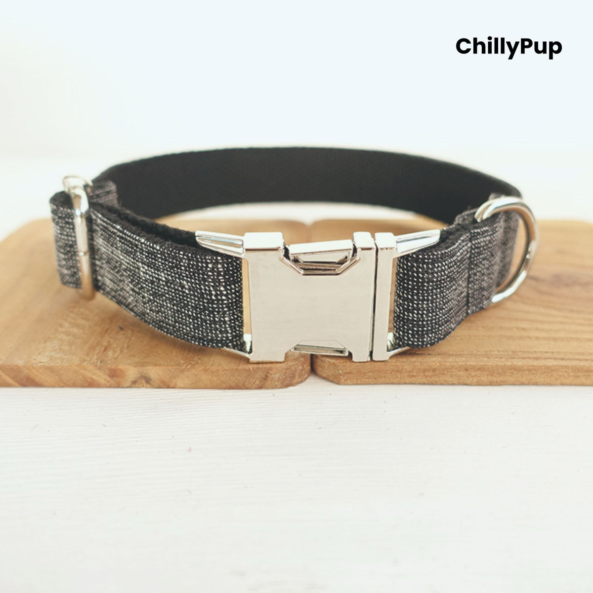 Grey dog collar with metal clip on a wooden board, branded 'ChillyPup'.