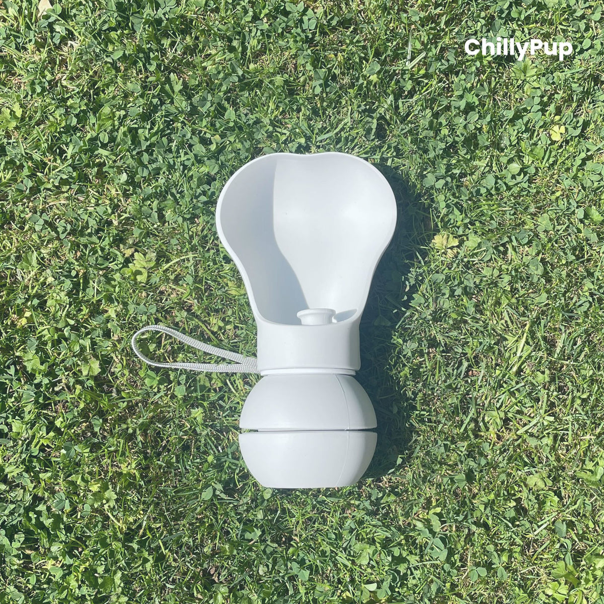 One Foldable silicone water bottle with drinking section on grass.